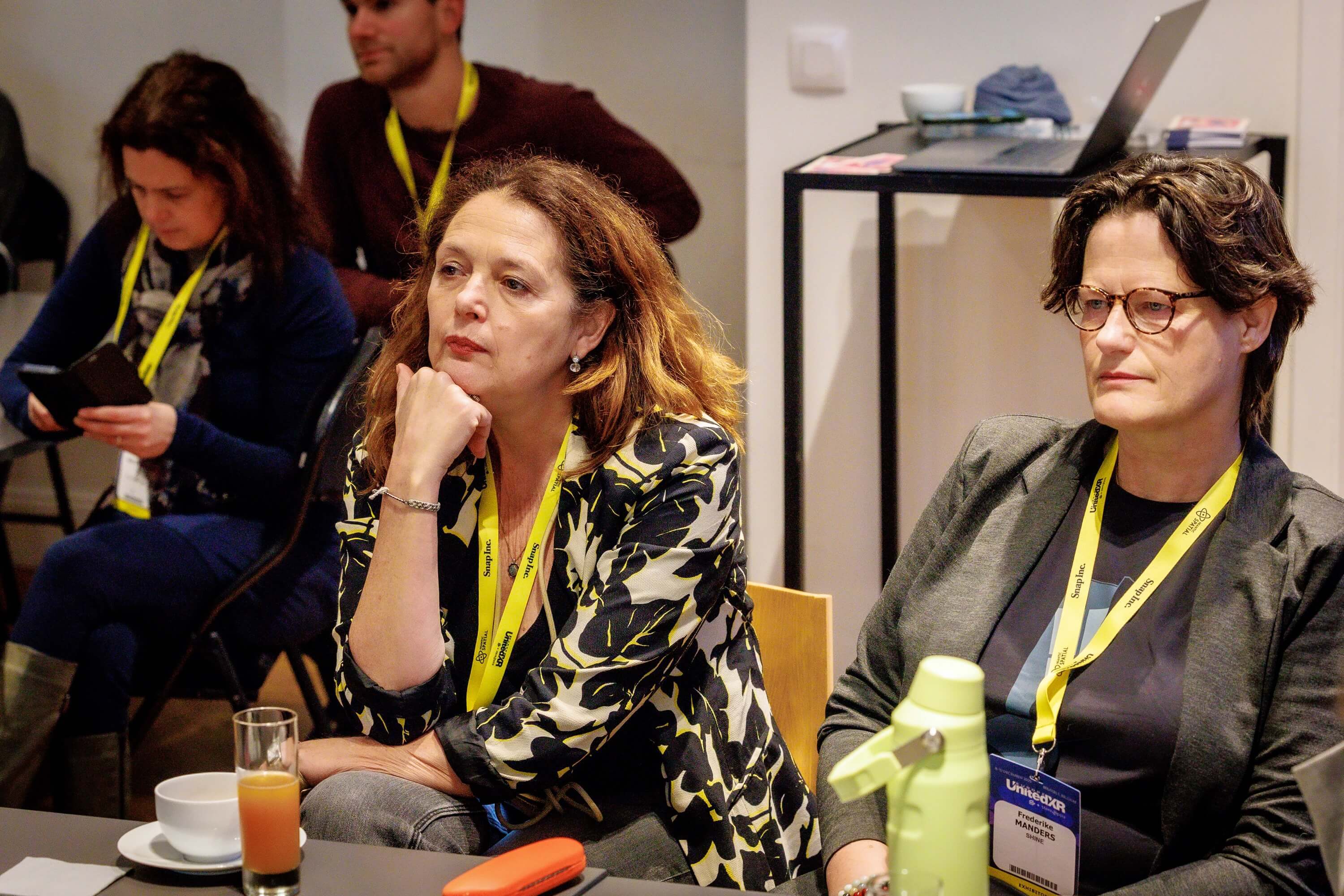 twee mensen in gesprek met andere mensen op de achtergrond